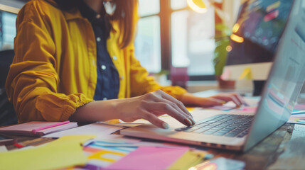 young female designer working on laptop at office desk, using modern technology in her creative occupation, focusing on graphic design project, planning and typing on computer.