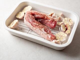 Pork belly and whole garlic in an oven dish