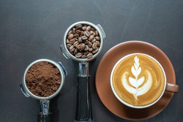 Top view of a cup of cafe latte with baskets of coffee beans and grind coffee