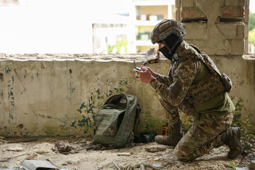 Fototapeta premium Military mission. Soldier in uniform with drone controller inside abandoned building, space for text