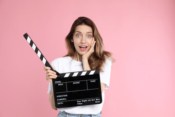 Making movie. Surprised woman with clapperboard on pink background