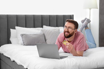 Online banking. Happy young man with credit card and laptop paying purchase at home