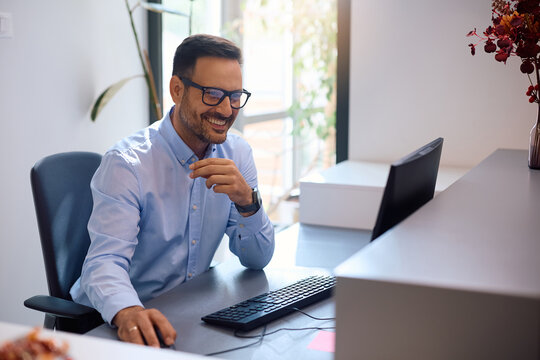 Happy entrepreneur working on desktop PC in office.