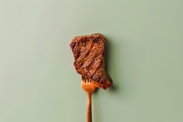 Grilled steak on a fork against a green background