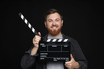 Making movie. Smiling man with clapperboard on black background