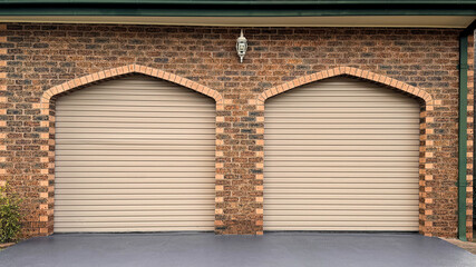 two cream color roller garage doors against arched frame on brick wall