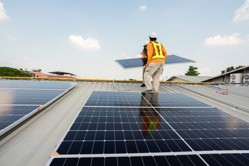 Men technicians carrying photovoltaic solar moduls on roof of factory on the morning. Installing a Solar Cell on a Roof. Solar panels on roof. Workers installing solar cell power plant eco technology.