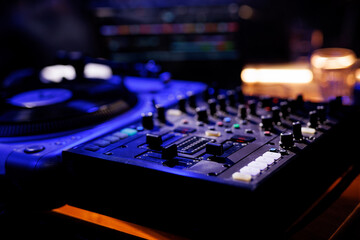 A close-up view of a professional DJ mixing console with various knobs and sliders.