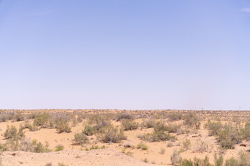 A vast desert with a clear blue sky. The sky is empty and the sun is shining brightly