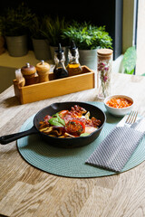 English Breakfast in cooking pan with fried eggs, sausages, bacon, mushrooms, beans and tomato