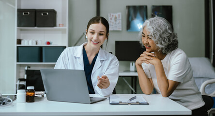 Female doctor consulting senior old patient filling form at consultation, talking to senior old...