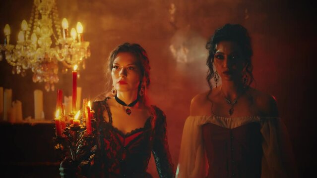 Real people two women vintage clothes white red dress. Fantasy Sexy girl beauty face walking in night dark room hand holding old style candlestick candles burning light. Gothic Mystery woman queen 4k