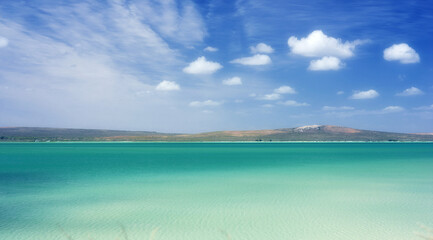 Obraz premium Blue sky, clouds and mountain with beach in nature for travel destination, vacation and calm water. Tropical island, coast and background of sea at sunset for holiday, peace and outdoor environment