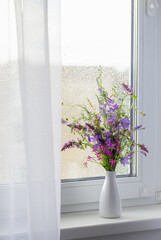 summer bouquet on white windowsill witrh  rain drops