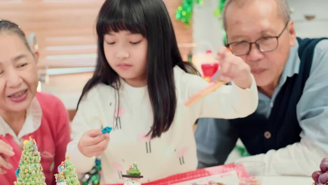 Happy Asian family spending times to prepare Chritsmas and Happy news year Celebrete. kids parent and grandparent doing ginger breads and bakery enjoy and dancing in kichen at home