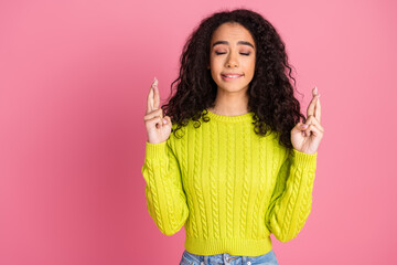 Photo portrait of youngster hispanic girl wavy brunette curly hair wearing green sweater crossed fingers please isolated on pink color background