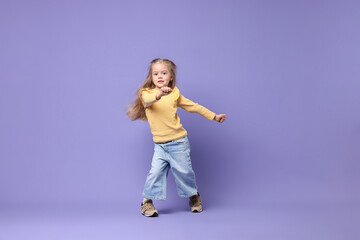 Cute little girl dancing on purple background