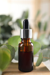 Aromatherapy. Bottle of essential oil and eucalyptus leaves on table