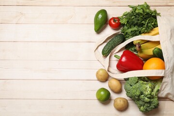 Vegan food delivery. Paper bag with different fresh vegetables and fruits on light wooden background, flat lay. Space for text