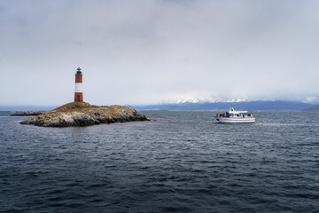 LES ECLAIREURS LIGHTHOUSE with sea lions resting on a rock and a boat in the waters of the Beagle...