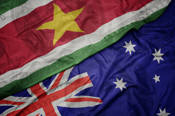 waving colorful flag of suriname and national flag of australia on the dollar money background. finance concept.