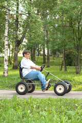 An elderly woman rides a toy car.