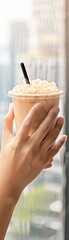 Fototapeta premium Close-up of hands holding a bubble tea cup with a cityscape background, bubble tea, urban lifestyle