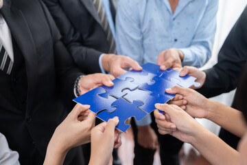 Multiethnic business people holding jigsaw pieces and merge them together as effective solution...