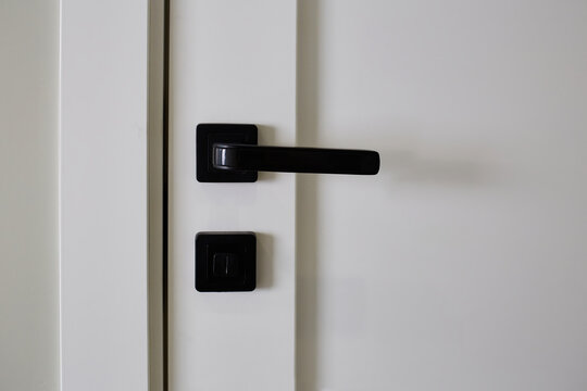White interior door with black doorknob. Element of interior design, close up. 