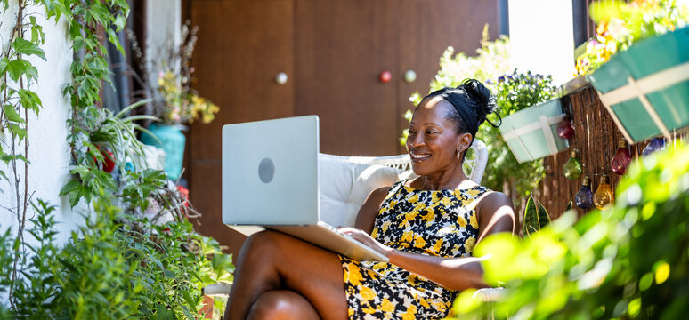Portrait of smiling woman using laptop while sitting on the balcony

