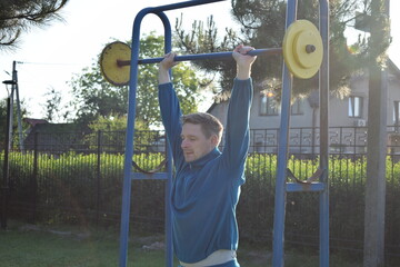 A dedicated young athlete puts in the hard work, vigorously training on gym equipment outdoors to...