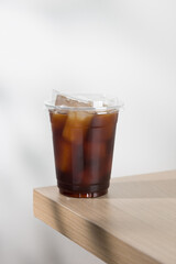 Iced americano in clear cup on wooden table.
