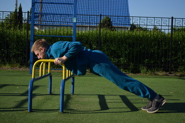 A dedicated young athlete puts in the hard work, vigorously training on gym equipment outdoors to...
