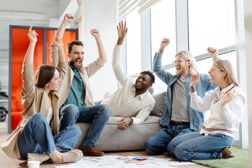 Excited business team celebrating success raising arms in office