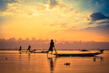 Myanmar travel attraction landmark - traditional Burmese fishermen sihouettes at Inle lake on sunset, Myanmar famous for their distinctive one legged rowing style