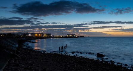 Long exposure blue hour image of shore sea wall & harbor with light starbursts