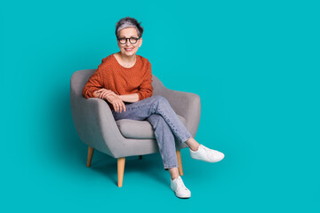 Full size photo of nice retired female sit armchair wear trendy brown outfit isolated on aquamarine color background