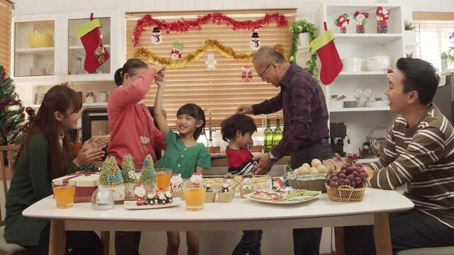 Happy Asian family spending times to prepare Chritsmas and Happy news year Celebrete. kids parent and grandparent doing ginger breads and bakery enjoy and dancing in kichen at home