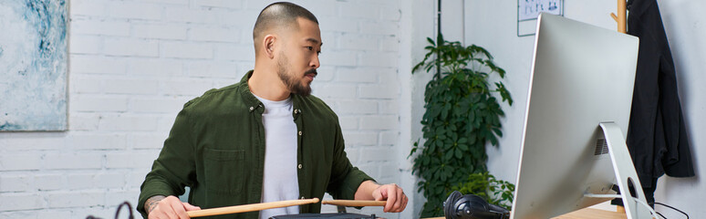 A handsome Asian man plays drums in a studio setting.