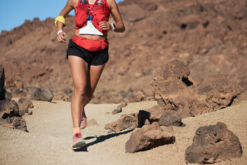 Female athlete run mountain race with hydratation trail vest for running