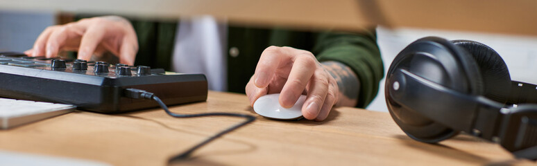 A handsome Asian man, wearing casual attire, is working in a recording studio. He is using a mixing...