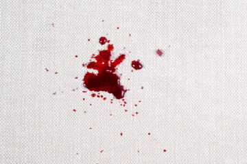 Red drops juice on the white upholstery of the sofa or carpet. Daily life dirty stain concept. top...