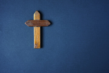 Wooden simple cross on blue background.