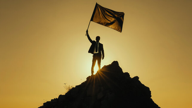 Silhueta de um homem em p&eacute; no topo da montanha segurando uma bandeira com um nascer do sol dram&aacute;tico no fundo, Conceito para supera&ccedil;&atilde;o, sucesso e realiza&ccedil;&atilde;o.