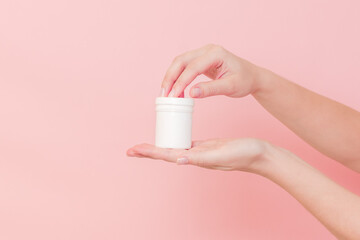 Hand with blank white plastic tube on pink background. Cosmetics beauty mockup for product branding