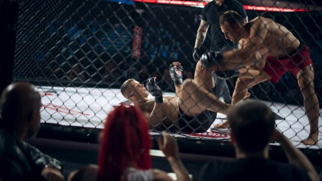 MMA Match: Fight Erupts with Explosive Energy as Two Strong Caucasian Men Exchange Rapid Strikes and Wrestle for Control. Audience Treated with a Thrilling Spectacle of Ground and Pound