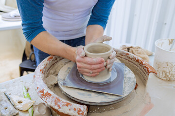 On potter wheel, potter hand sculpts soft clay with wet hands is crafting clay dishes