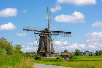 Spring landscape view with beautiful traditional windmill under blue sky, Dutch agriculture in...