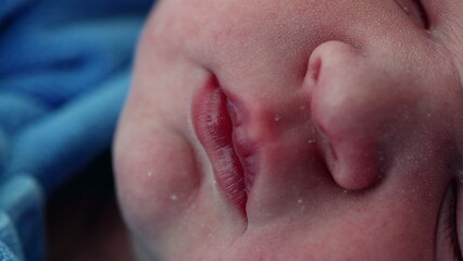 Sleeping Newborn baby infant's mouth and face in macro detail during initial hours of life after birth in serene peaceful slumber