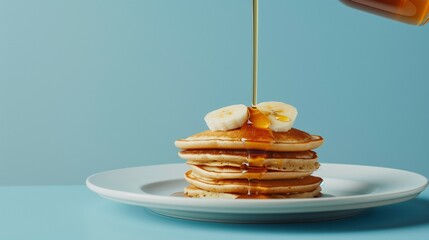 Close-up of golden syrup being poured over a stack of pancakes on a plate, creating a mouth-watering breakfast scene.